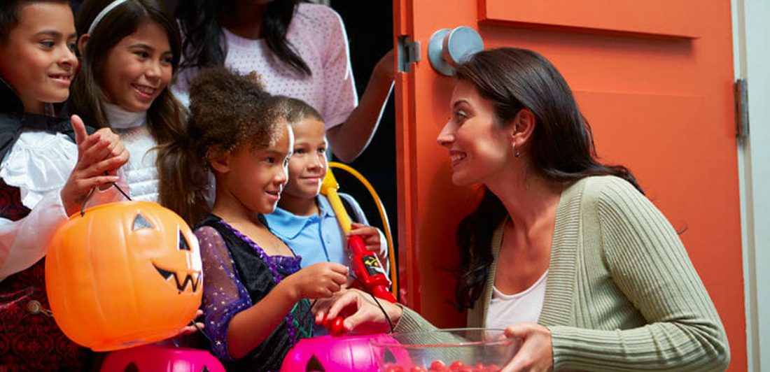 Image of woman giving trick or treaters candy at the door