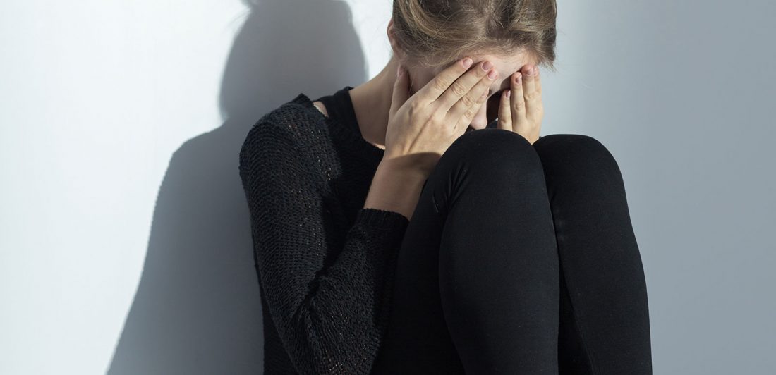 Image of woman covering her face sitting on the floor