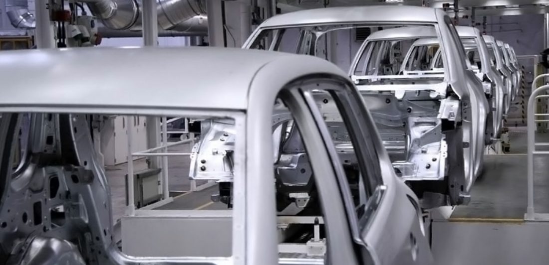 Image inside a vehicle manufacturing plant with metal car frames on an assembly line