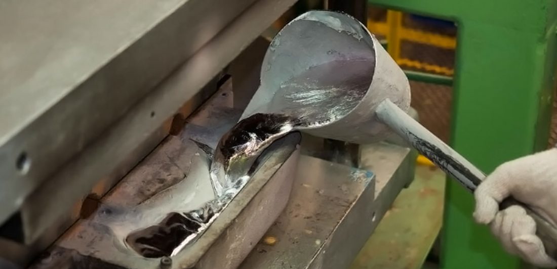 Image of worker pouring melted metal into a machine