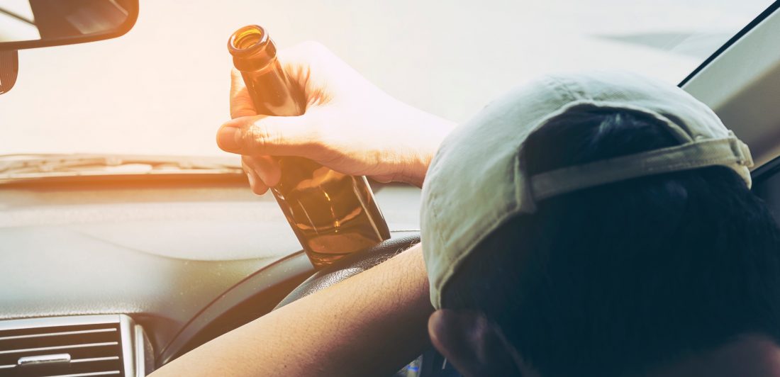 Man in vehicle holding a beer bottle